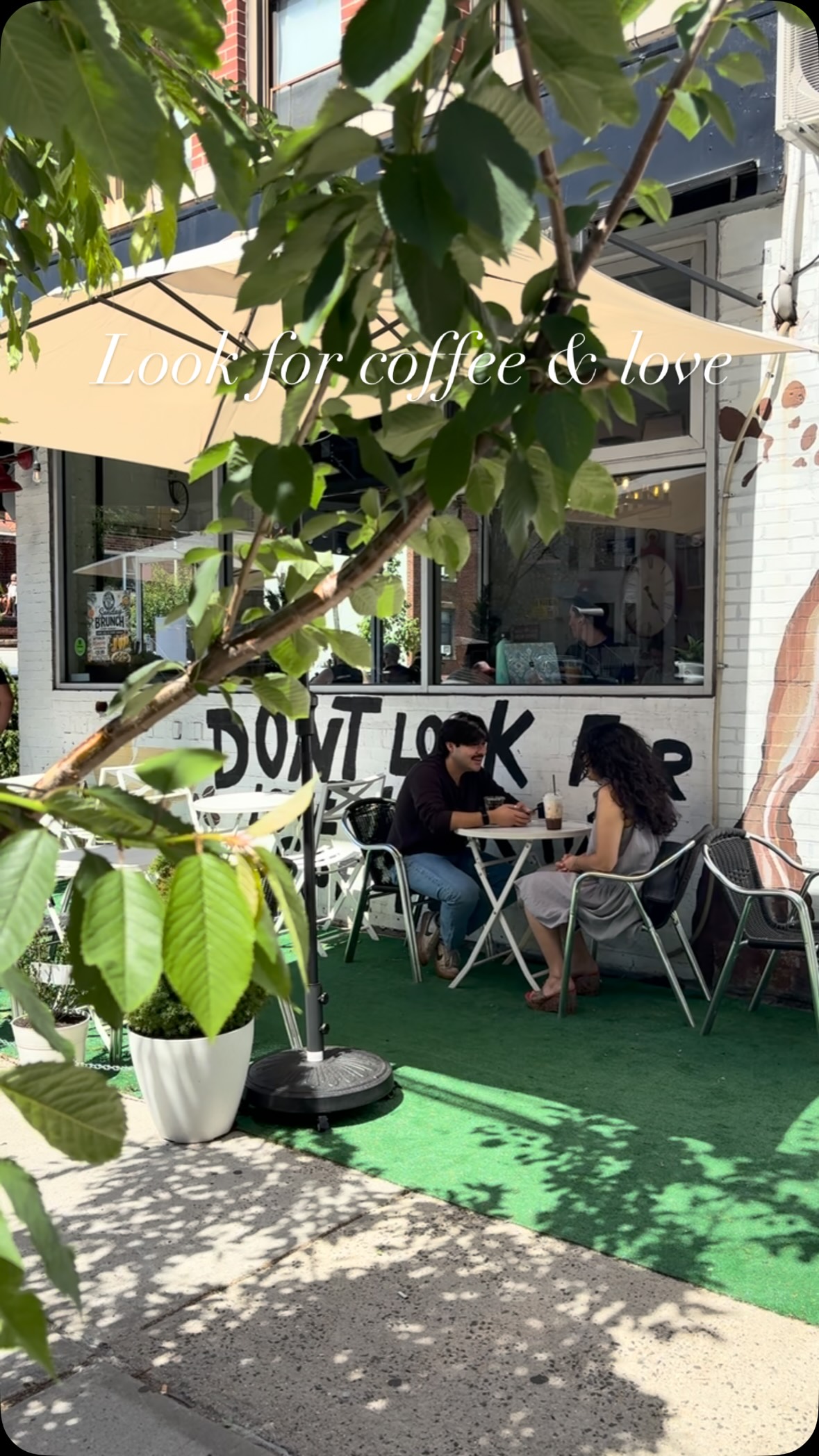 The Coffee Ave corner — mural wall, green turf seating and a couple having coffee